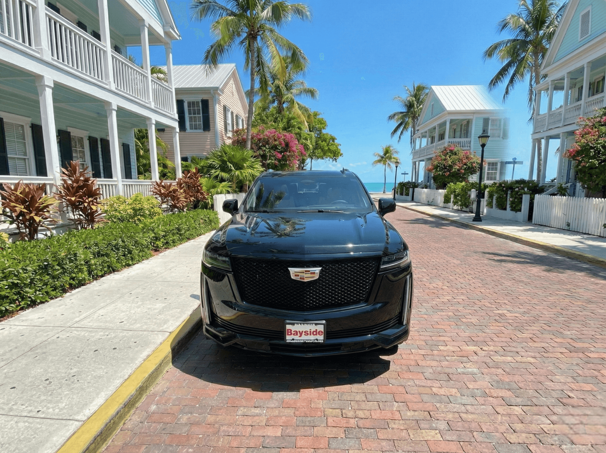 Black Cadillac Escalade on a palm-lined Key West street near the ocean